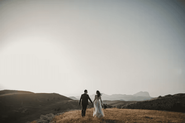 Les mariés de dos, marchant main dans la main au coucher du soleil