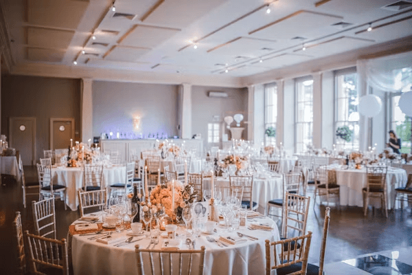 Salle de réception dressée avec tables rondes et centres de table fleuris