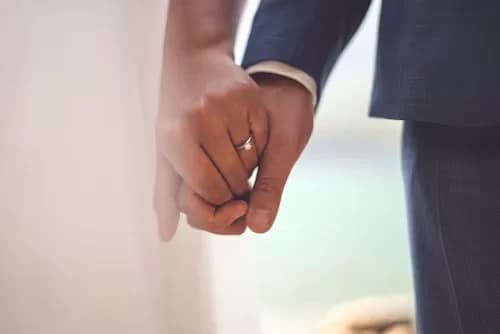 Les mains d'un couple de mariés qui se tiennent, l'alliance visible au doigt